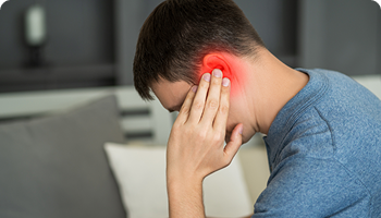 Man holding his head with one hand and his ear with the other, with a red glow around the ear indicating pain or infection, possibly an earache or tinnitus.