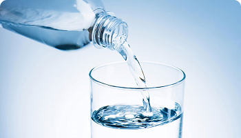 Clear water being poured from a plastic bottle into a glass