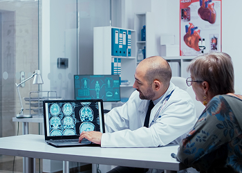 A doctor showing brain scan images on a laptop to an older female patient